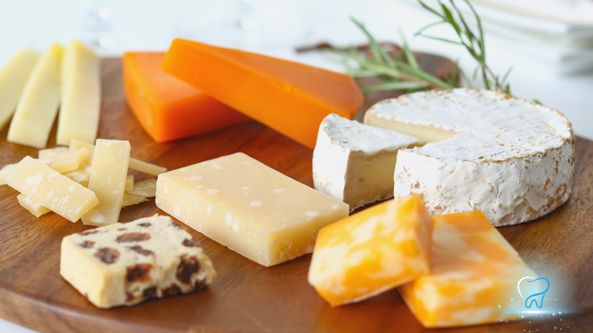Assorted cheeses on a wooden board, including wedges, cubes, and a round soft cheese with herbs