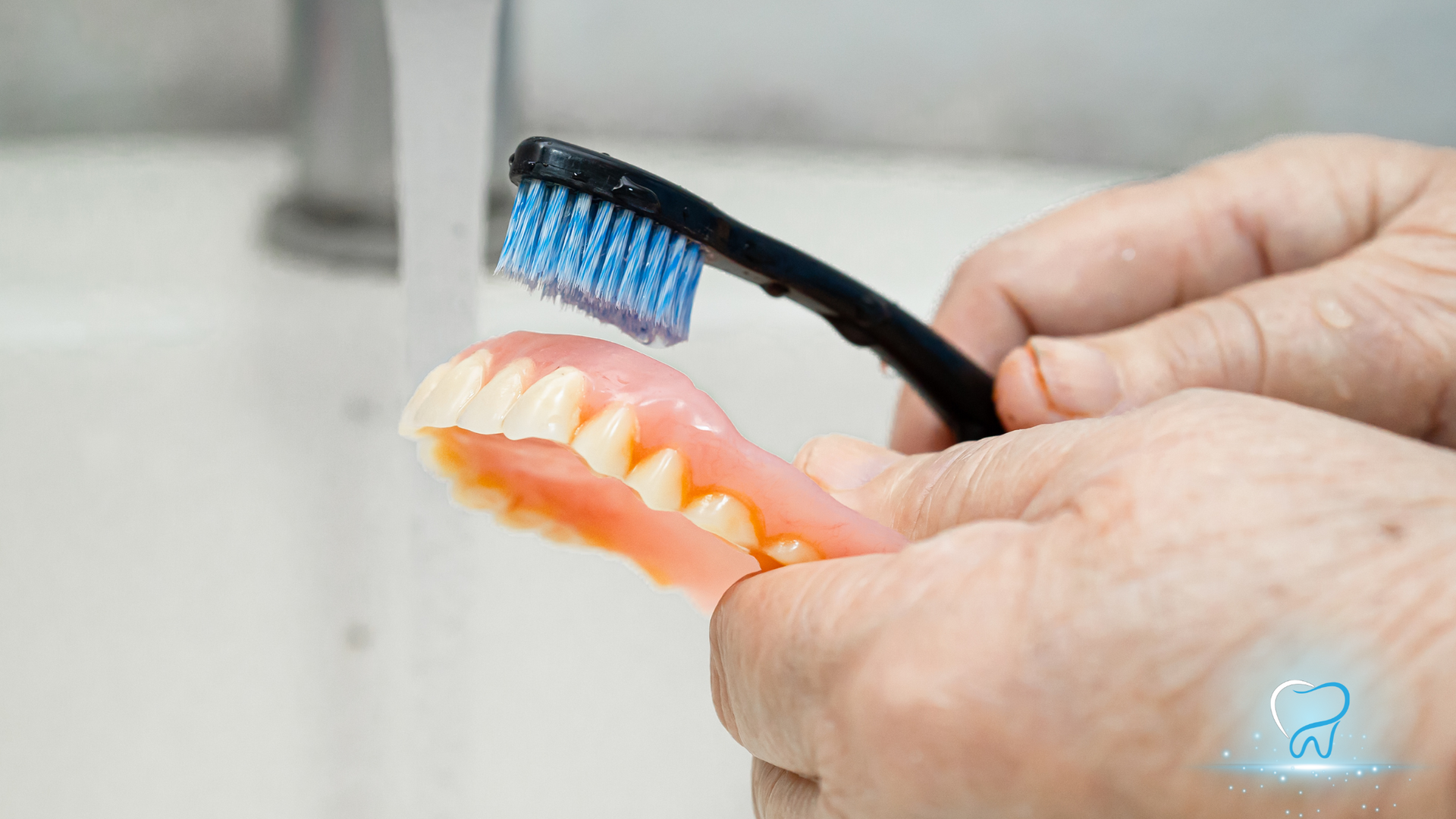 Hands holding two toothbrushes near dental models, one with blue bristles and one orange.