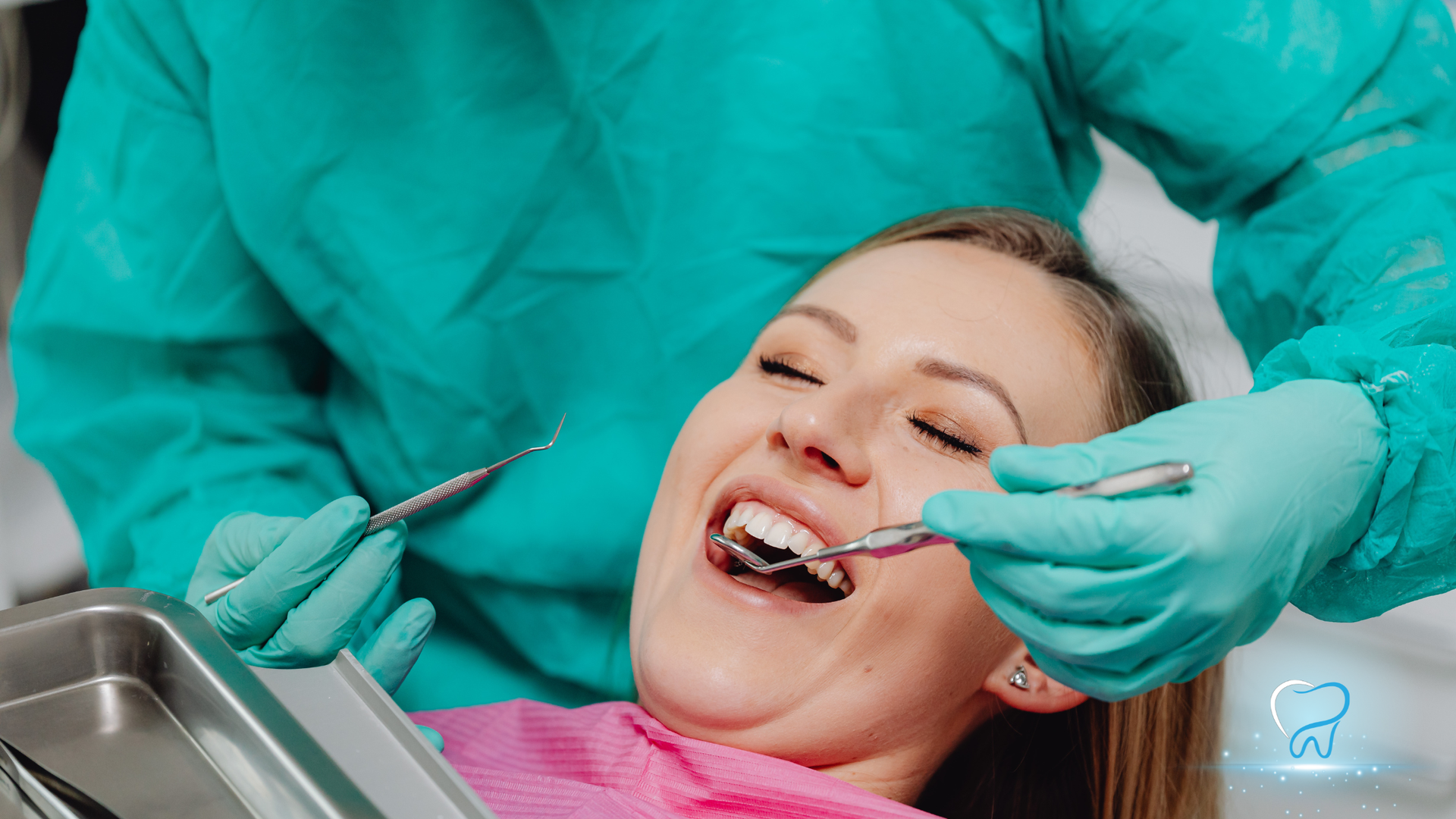 Dentist examining a smiling patient’s teeth with a mirror and tools in a dental chair