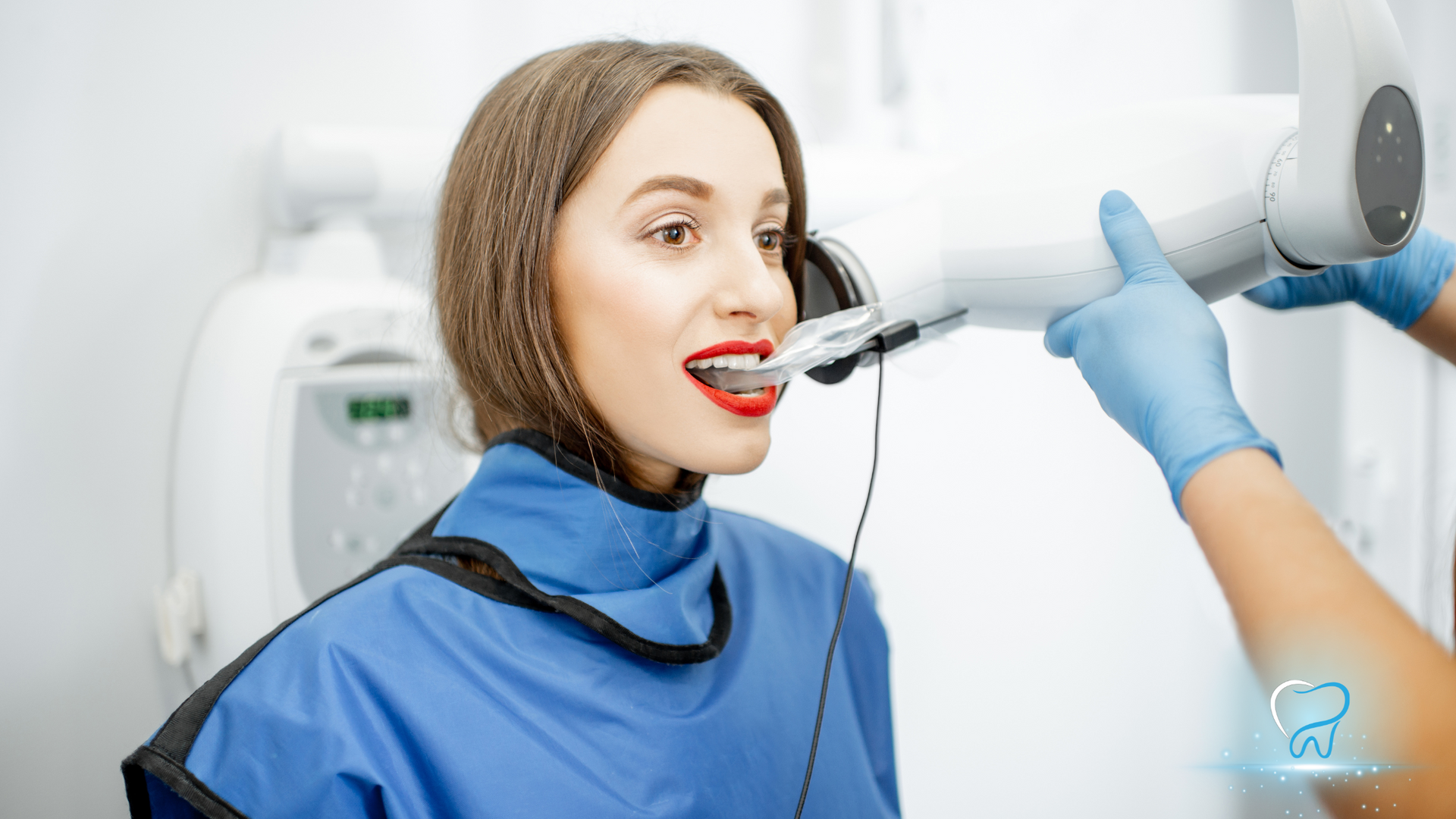 Dental patient in blue bib undergoing a scan by a clinician with handheld 3D imaging device