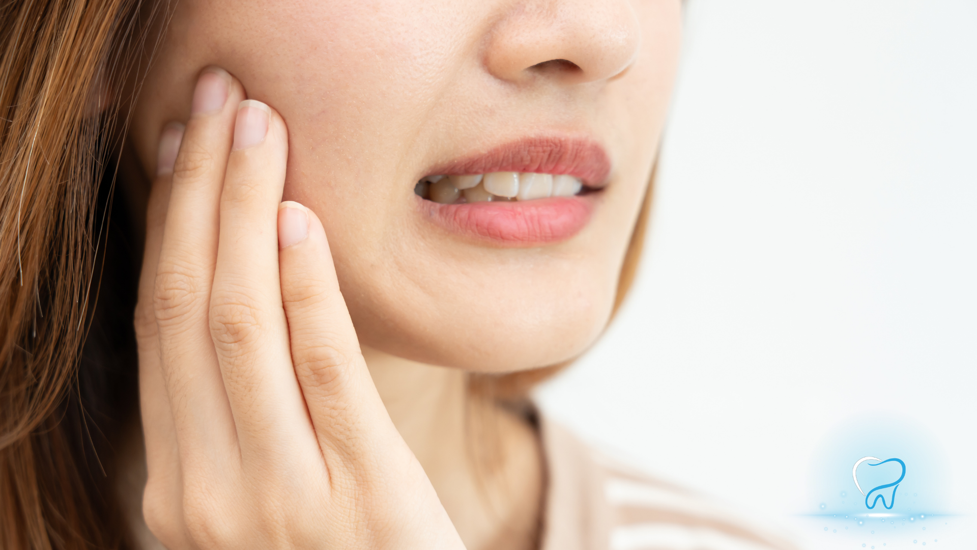 Close-up of a person touching their cheek, suggesting tooth or jaw pain.