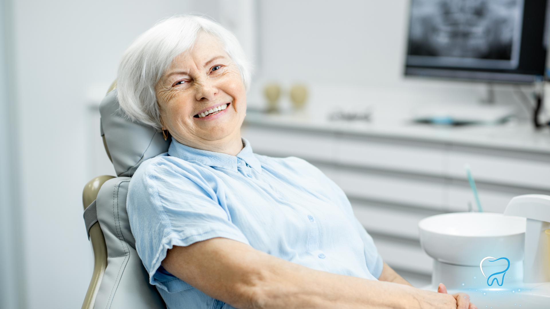 Smiling patient reclining in a dental chair with a dentist’s sink and tools nearby