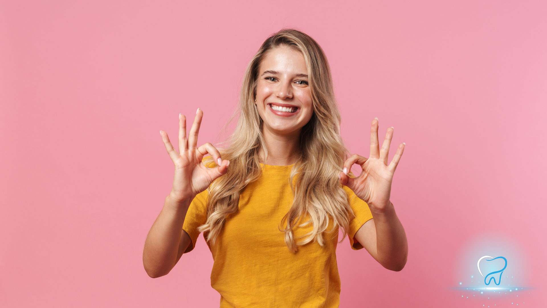 Smiling woman in a yellow shirt making OK signs against a pink background