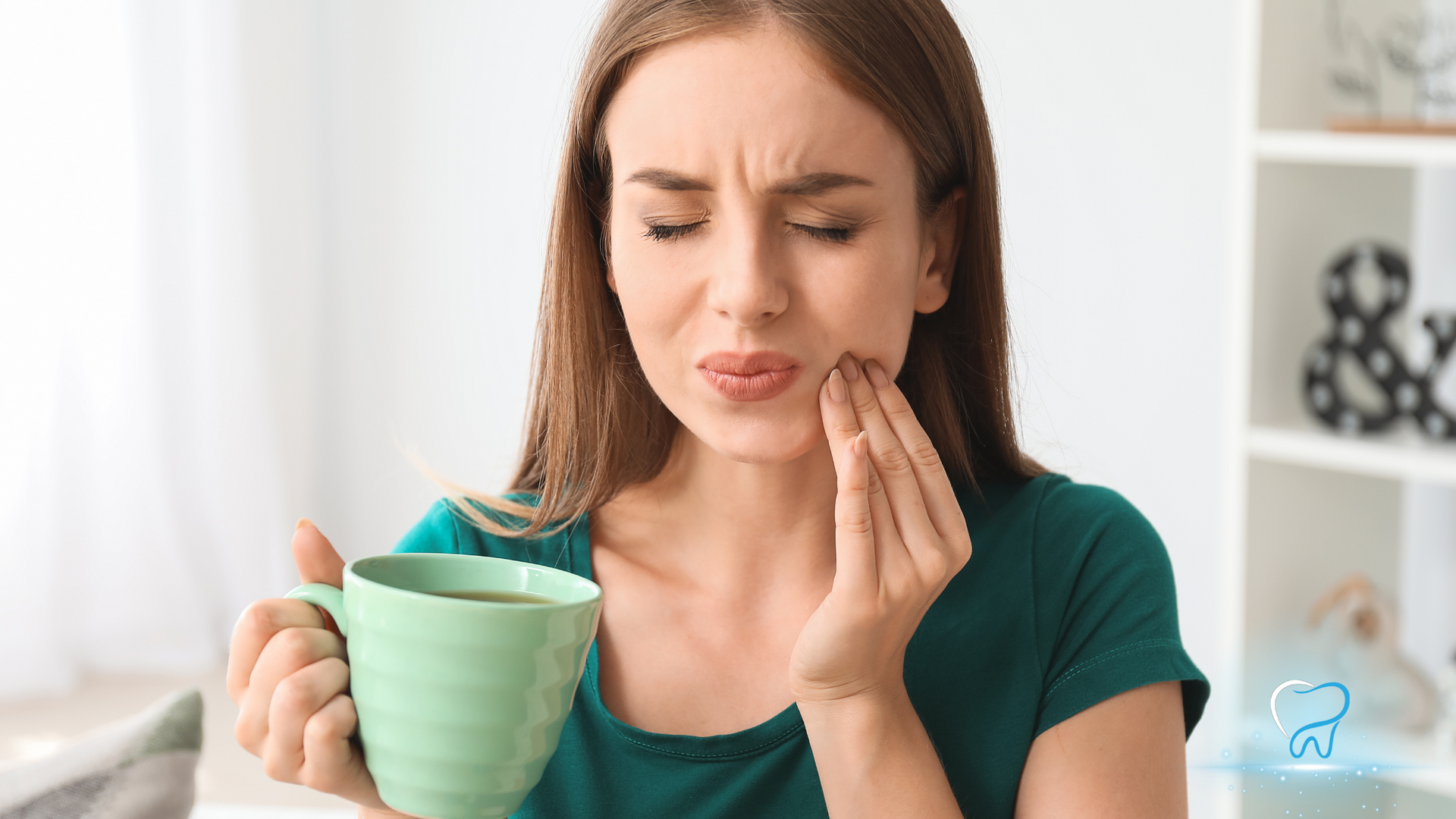 Woman holding a mug and touching her cheek with a pained expression in a bright kitchen