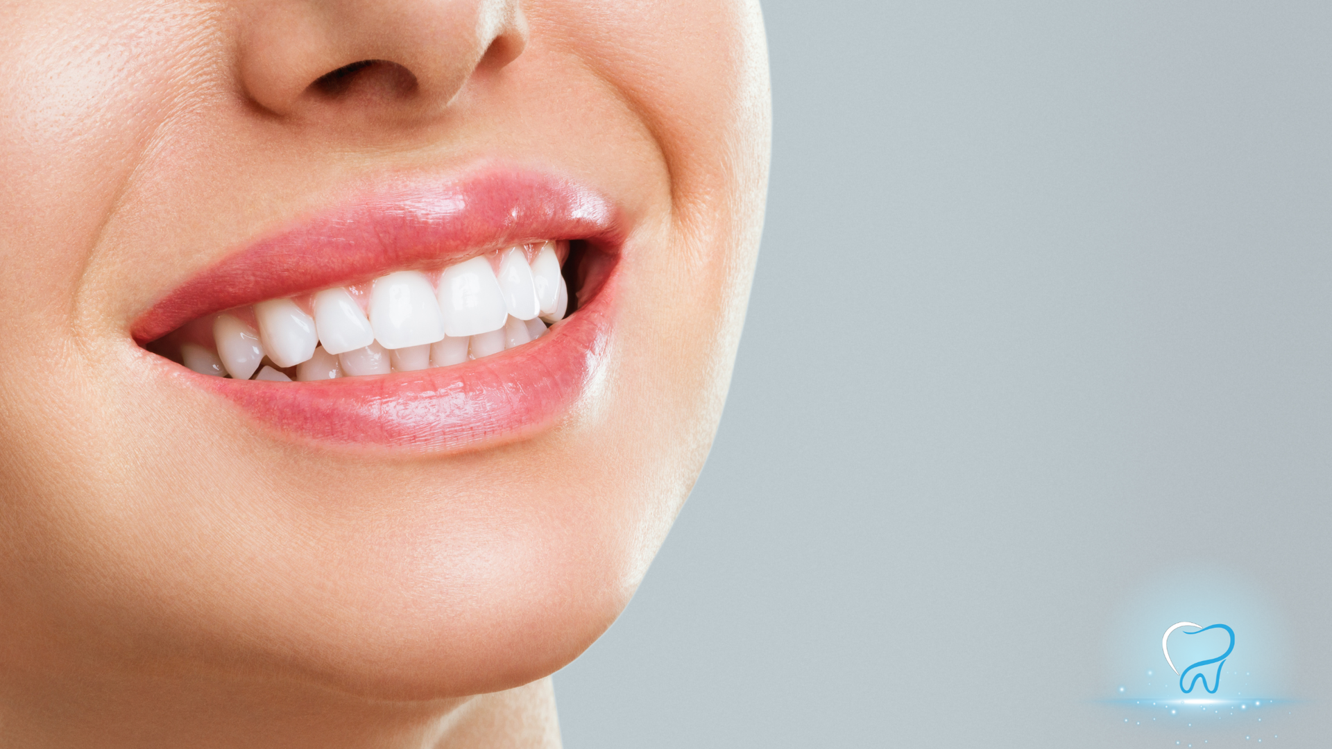 Close-up of a smiling mouth with white teeth and pink lips on a light gray background