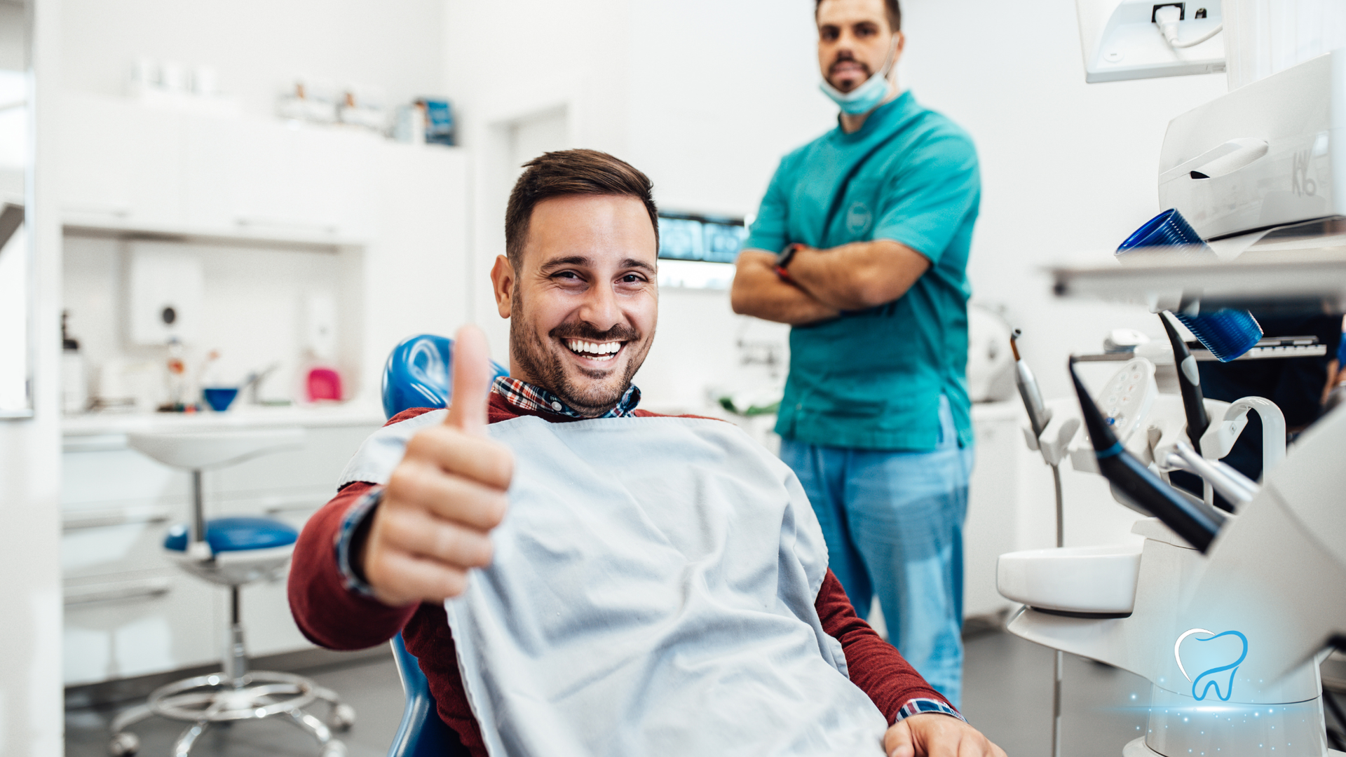 Smiling dental patient giving thumbs up in a clinic, with a dentist standing behind him.