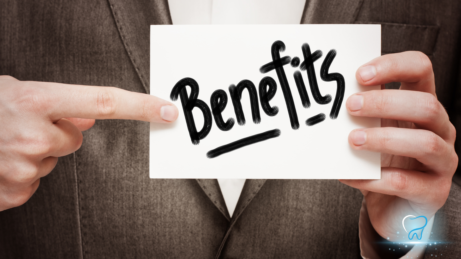 Hands holding a card with the word “Benefits” written in bold black letters.