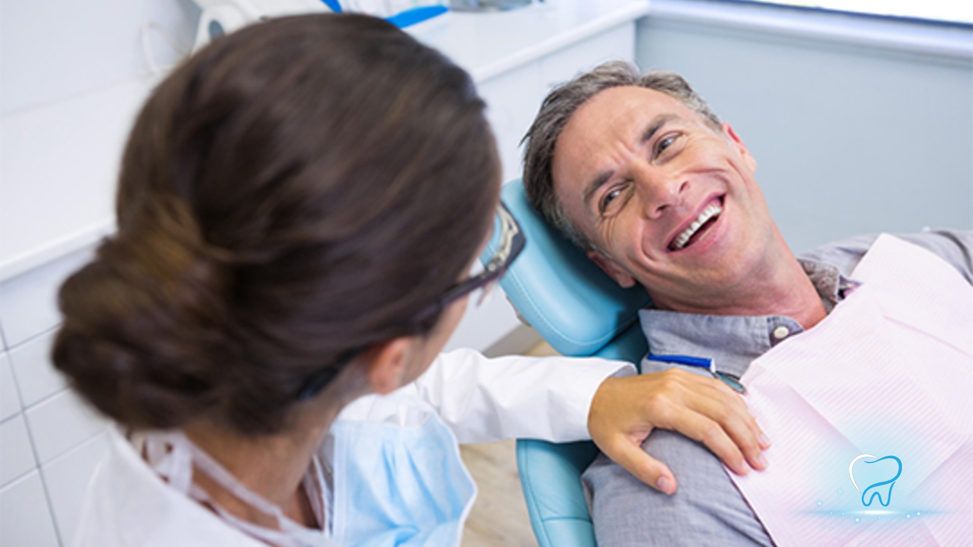 Dentist examining a smiling patient in a dental chair with a mouth mirror and blue headrest