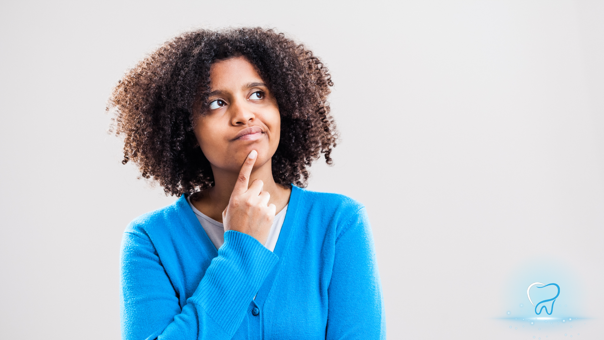 Person in a blue sweater looking thoughtful against a light background