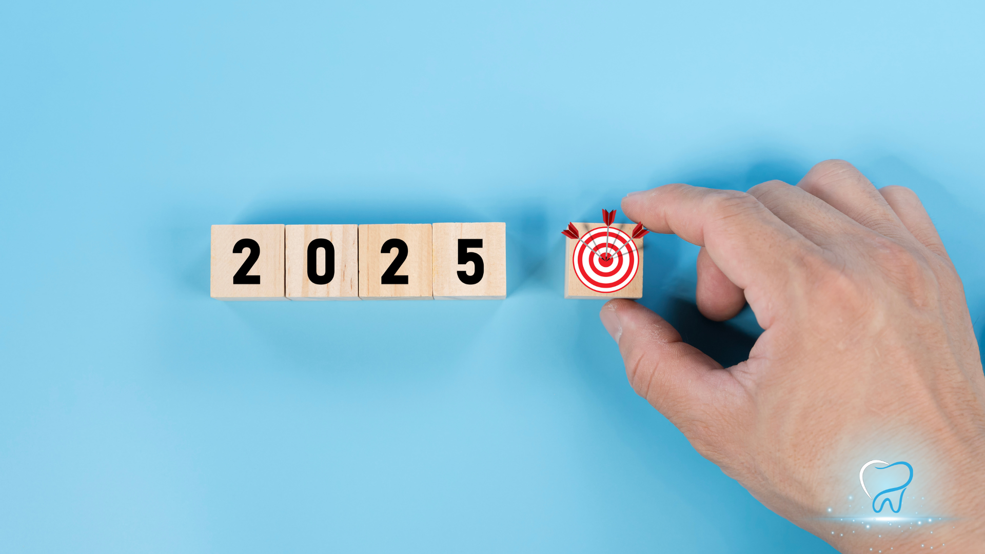 Hand placing a target block next to 2025 blocks on a blue background
