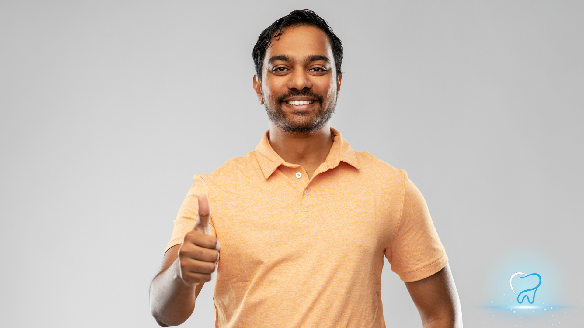 Smiling man in an orange polo giving a thumbs-up against a light gray background.