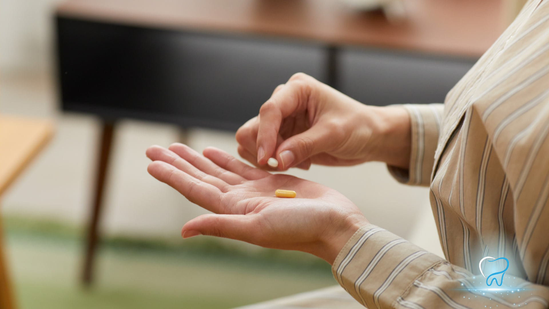 Person holding an open palm while placing a small pill into it indoors, with a blurred couch in the background