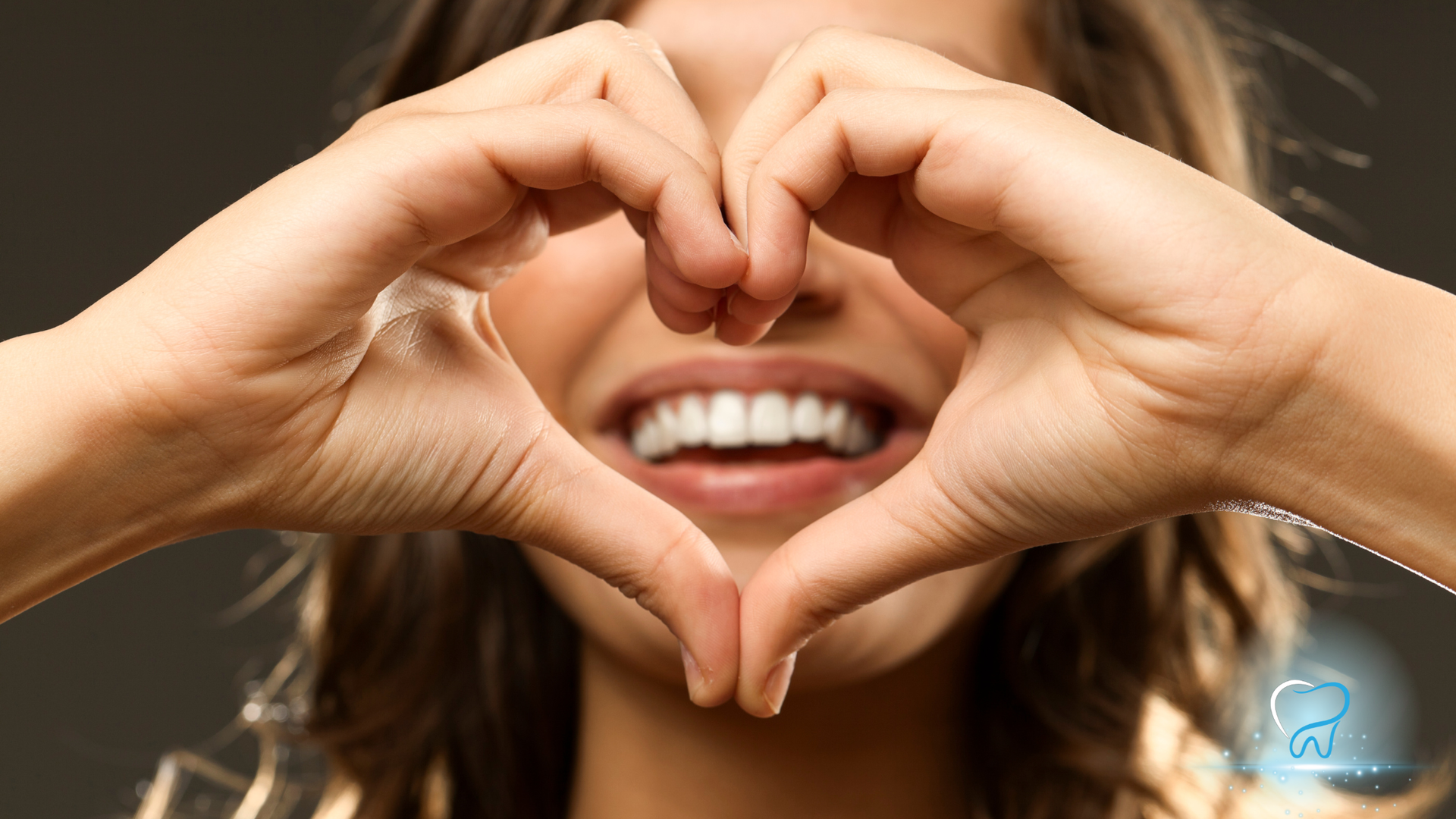 Close-up of hands forming a heart around a smiling mouth with white teeth