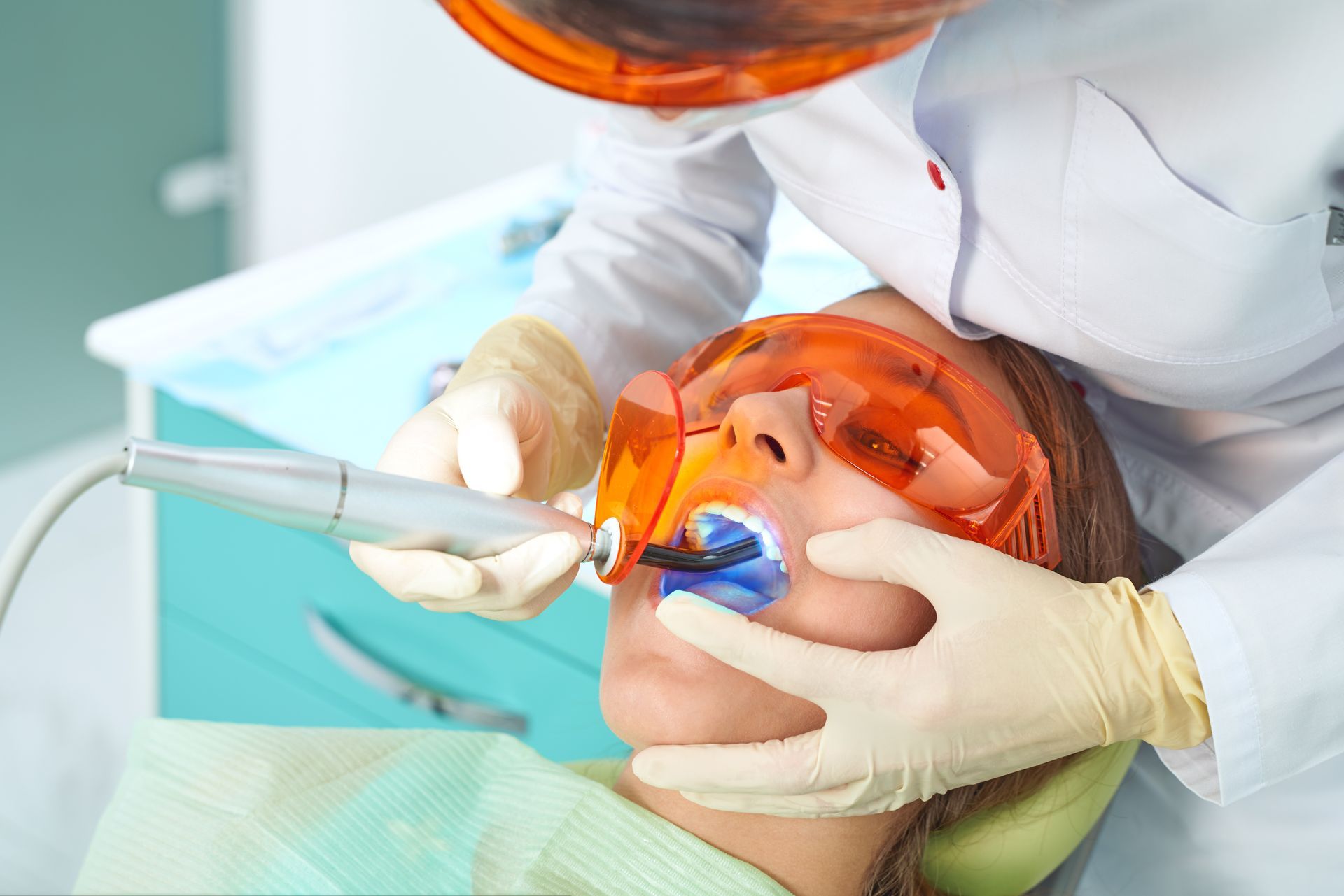 Dentist treating a patient with an orange face shield in a dental clinic