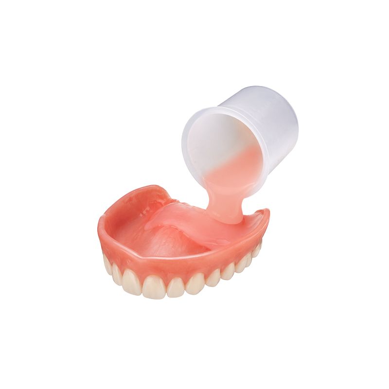 Dentures in a pink gum model being poured with pink liquid from a small cup