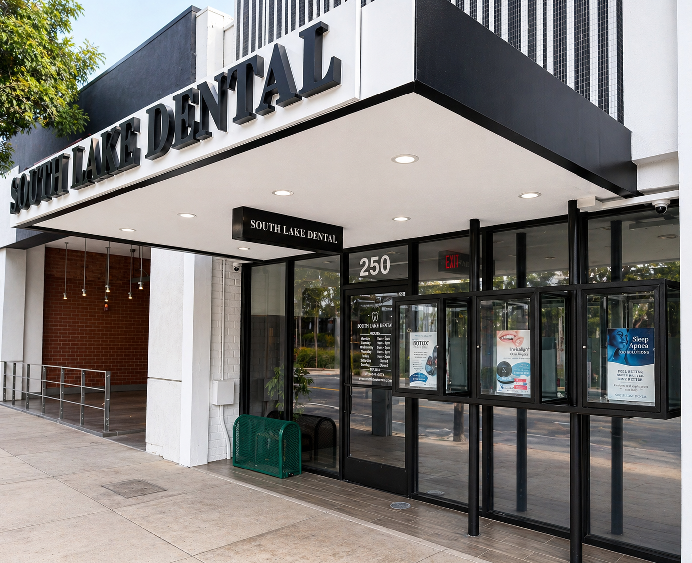 Exterior of a dental clinic with glass entrance, black awning, and “DENTAL” signage above the sidewalk