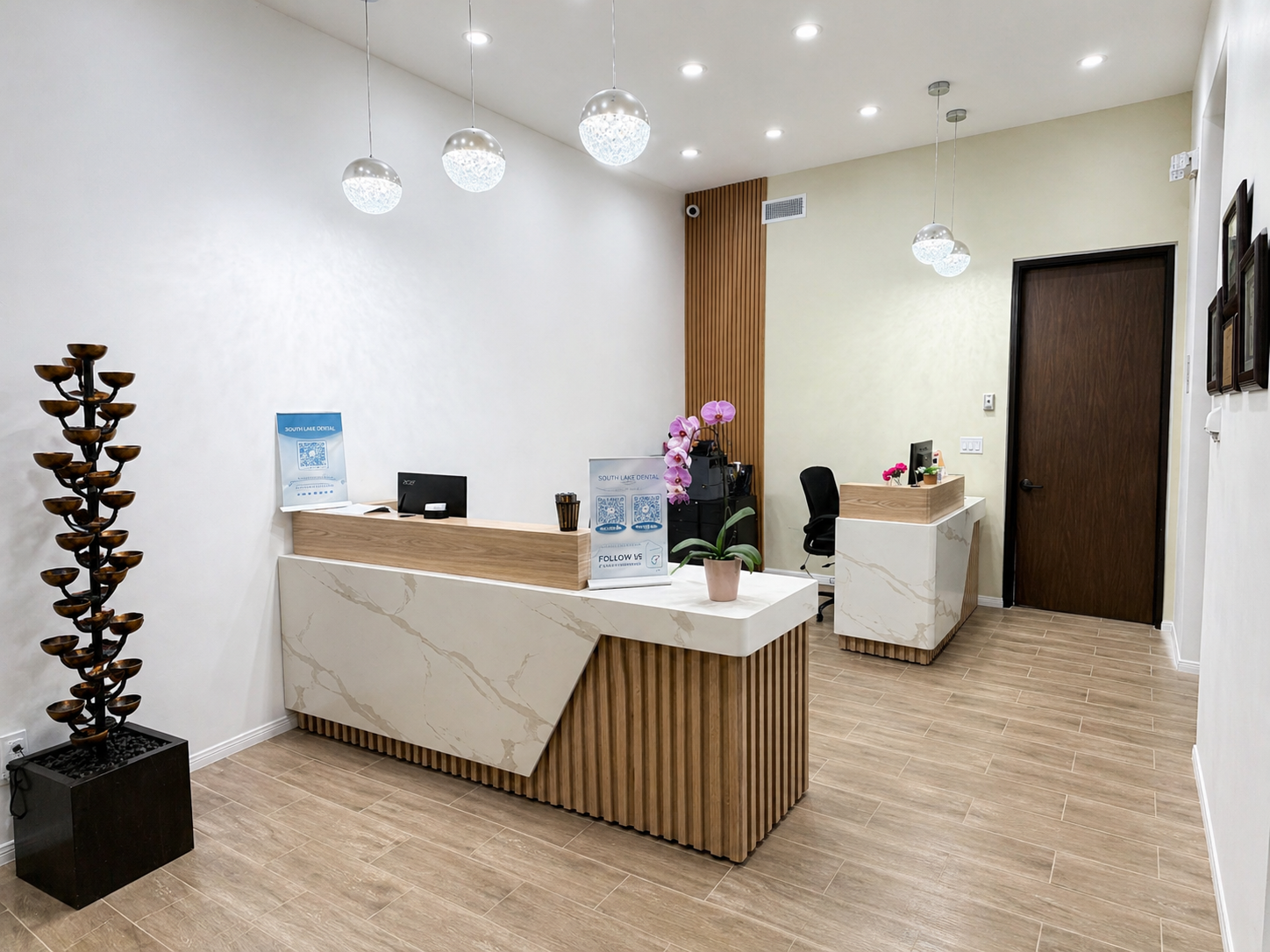 Modern office lobby with white walls, wood reception desk, pendant lights, and a decorative flower arrangement
