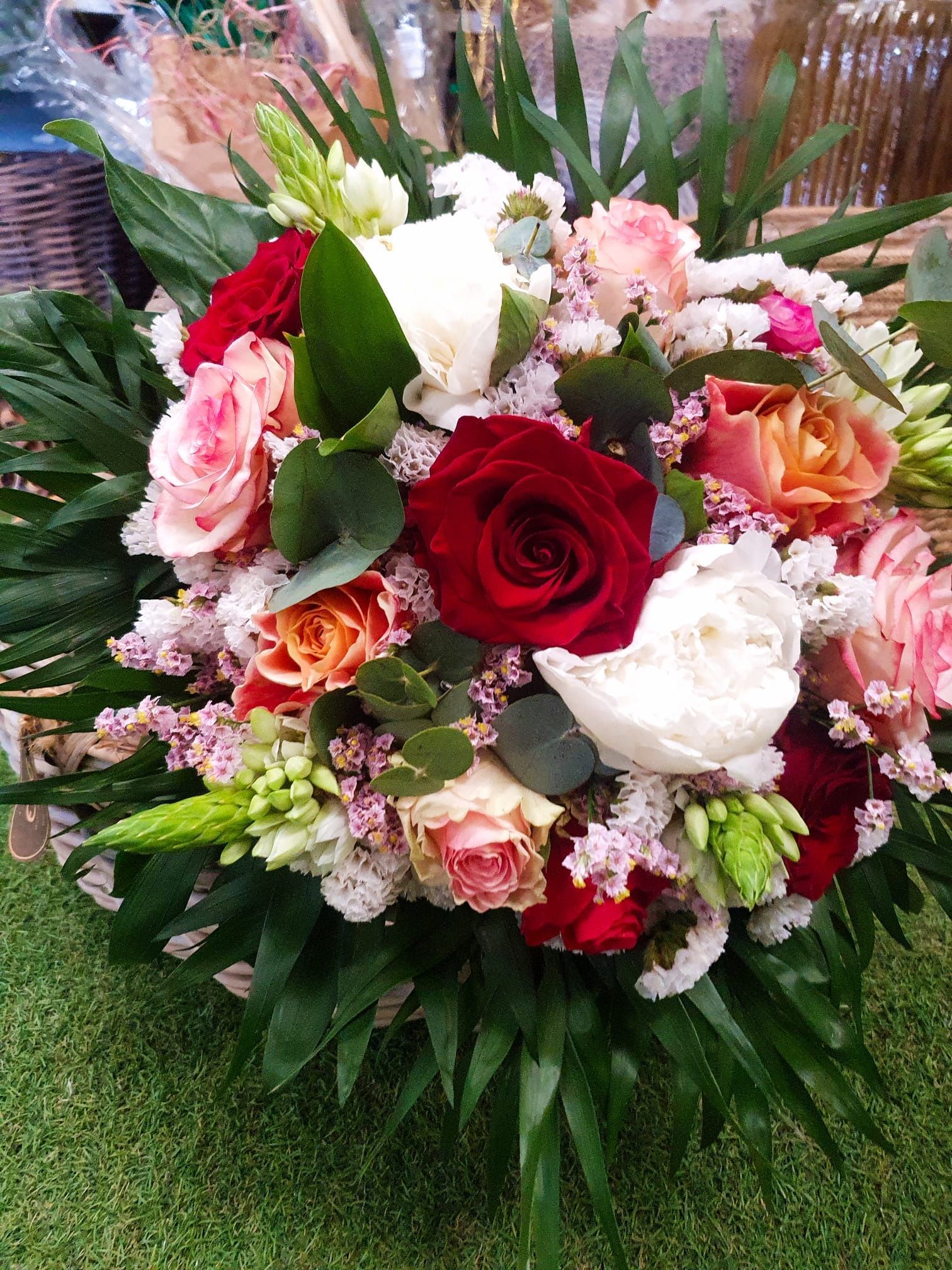 Un vivace bouquet di rose rosse, rosa e arancioni con accenti bianchi e fogliame verde.