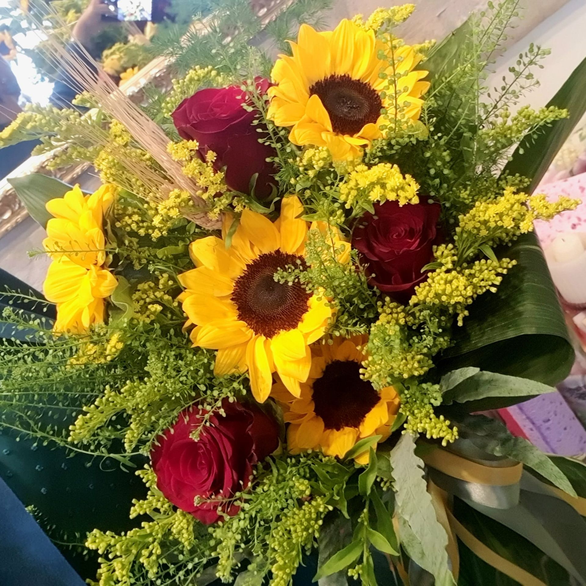 Bouquet con girasoli, rose rosse e fiori di riempimento gialli.