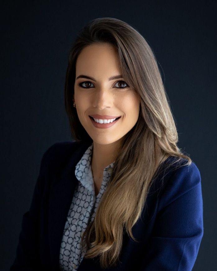 A woman in a blue jacket and white shirt is smiling for the camera.