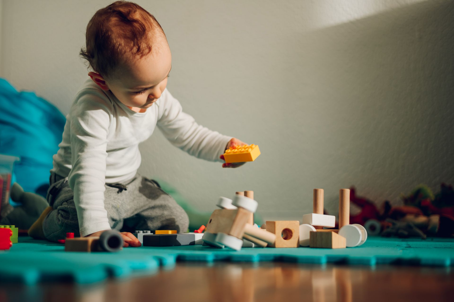 A baby is sitting on the floor playing with wooden blocks.