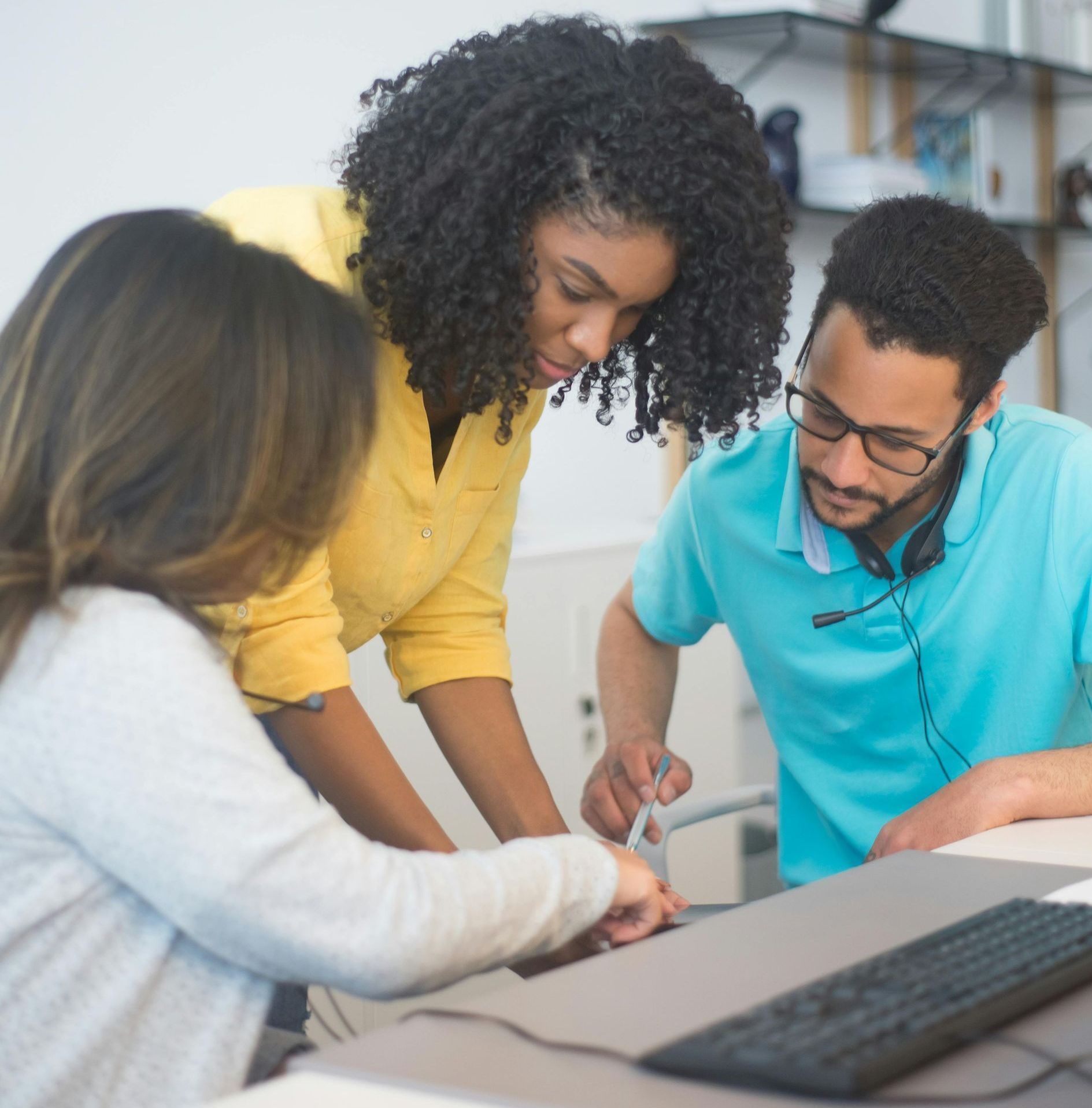 A man and two women are looking at a computer screen