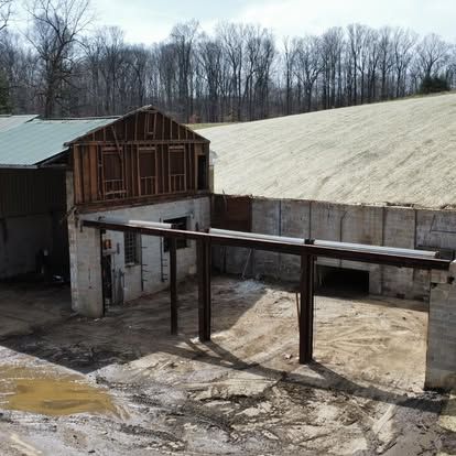 Partial barn demolition with remaining foundation walls and steel beams by Elevated Excavation