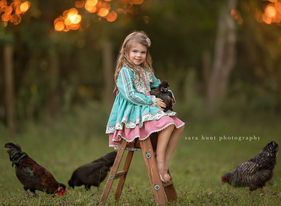 Girl holding chicken while sitting — Pearland, TX — Sara Hunt Photography