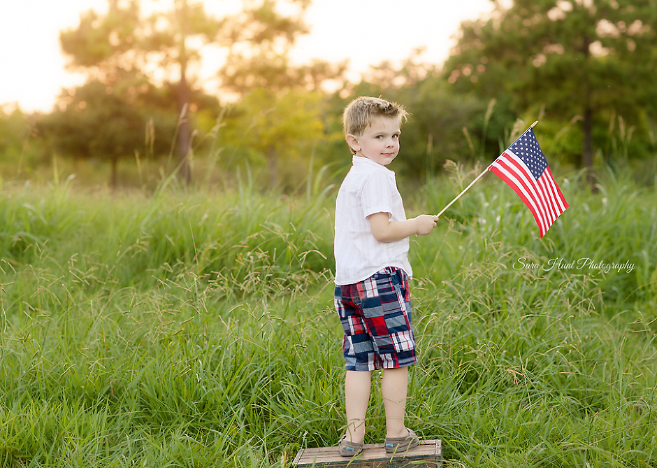Boy holding an American flag while showing his back — Pearland, TX — Sara Hunt Photography