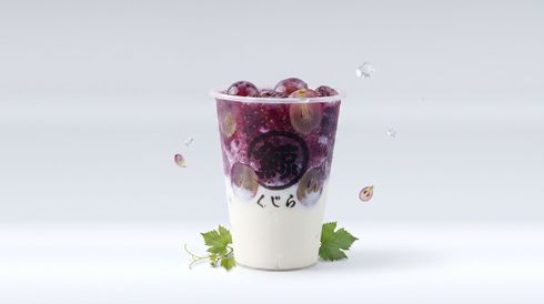 Milk tea with purple fruit topping in a clear cup on a white background