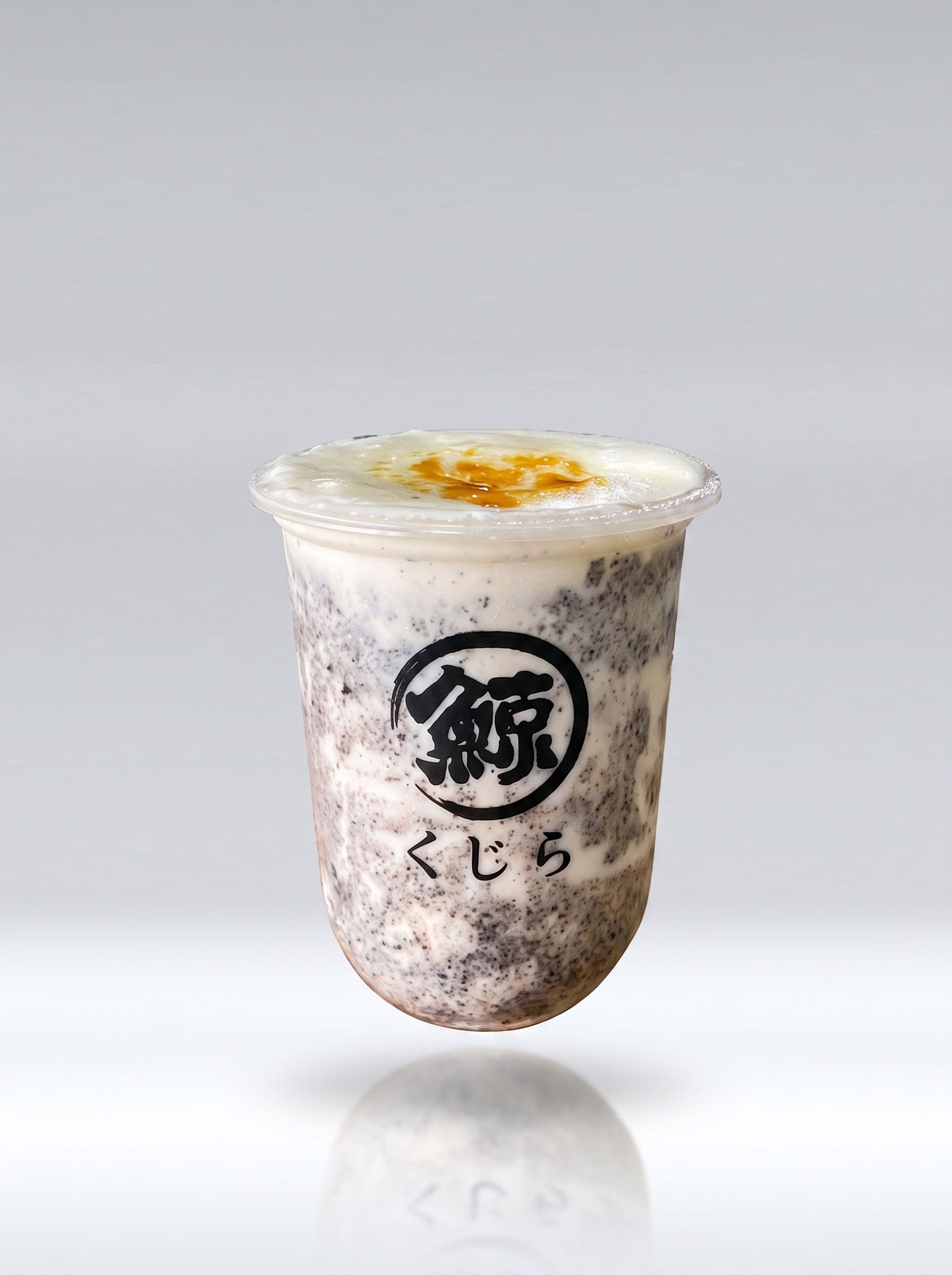 Iced milk tea in a clear cup with Japanese logo and a foamy top, on a plain background