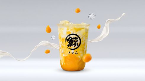 Orange bubble tea cup with ice and splashing orange fruit pieces on a light gray background