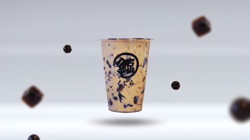 Iced milk tea in a clear cup with black tapioca pearls floating around it