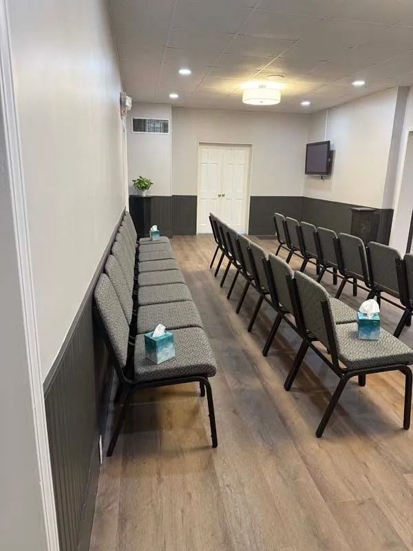 Small meeting room with rows of black chairs and a gray bench along the wall