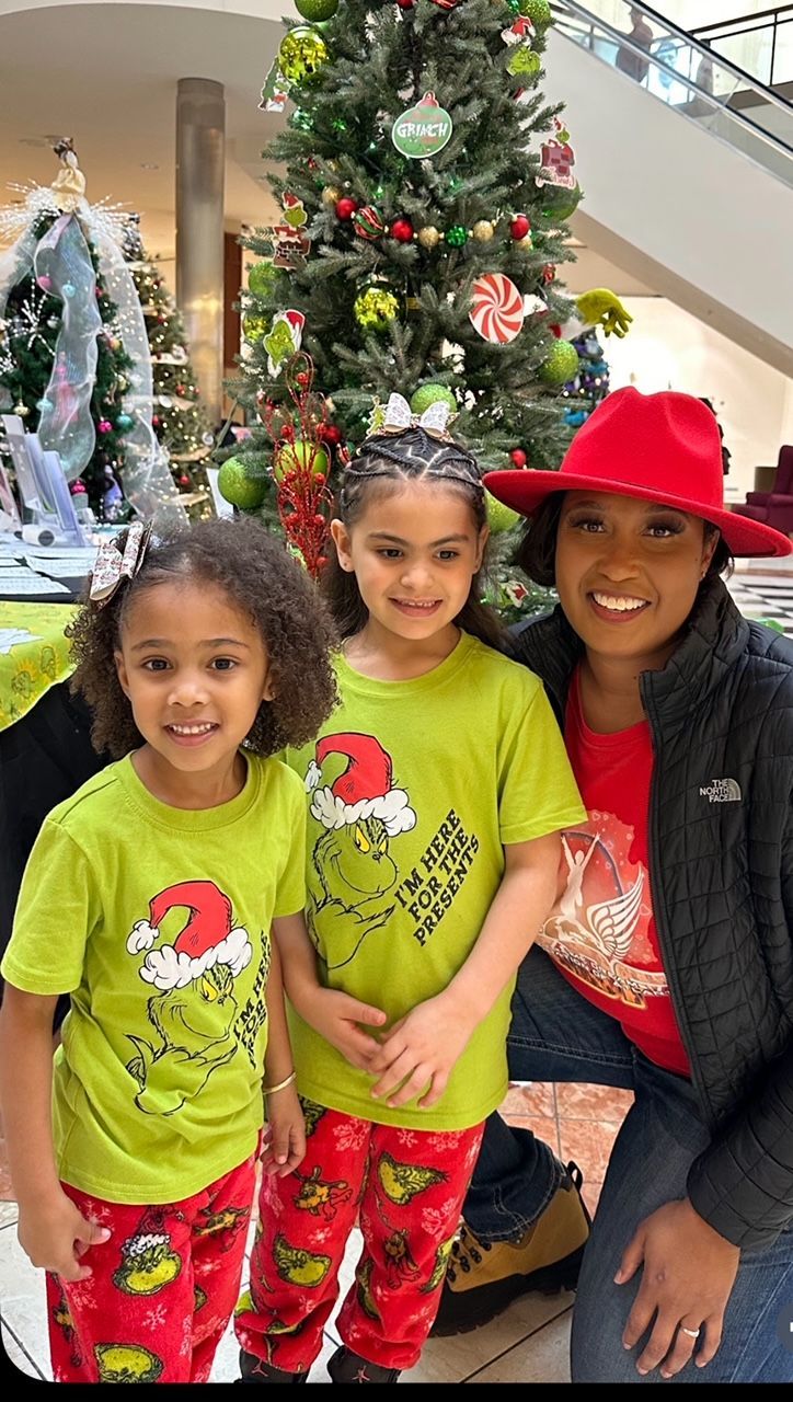 Three people smiling in festive pajamas beside a decorated Christmas tree.