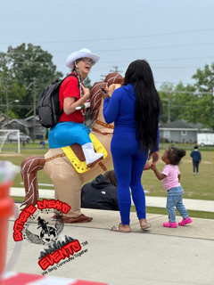 Woman on a horse costume at an outdoor event, with a child nearby and a cowboy hat worn by the rider.