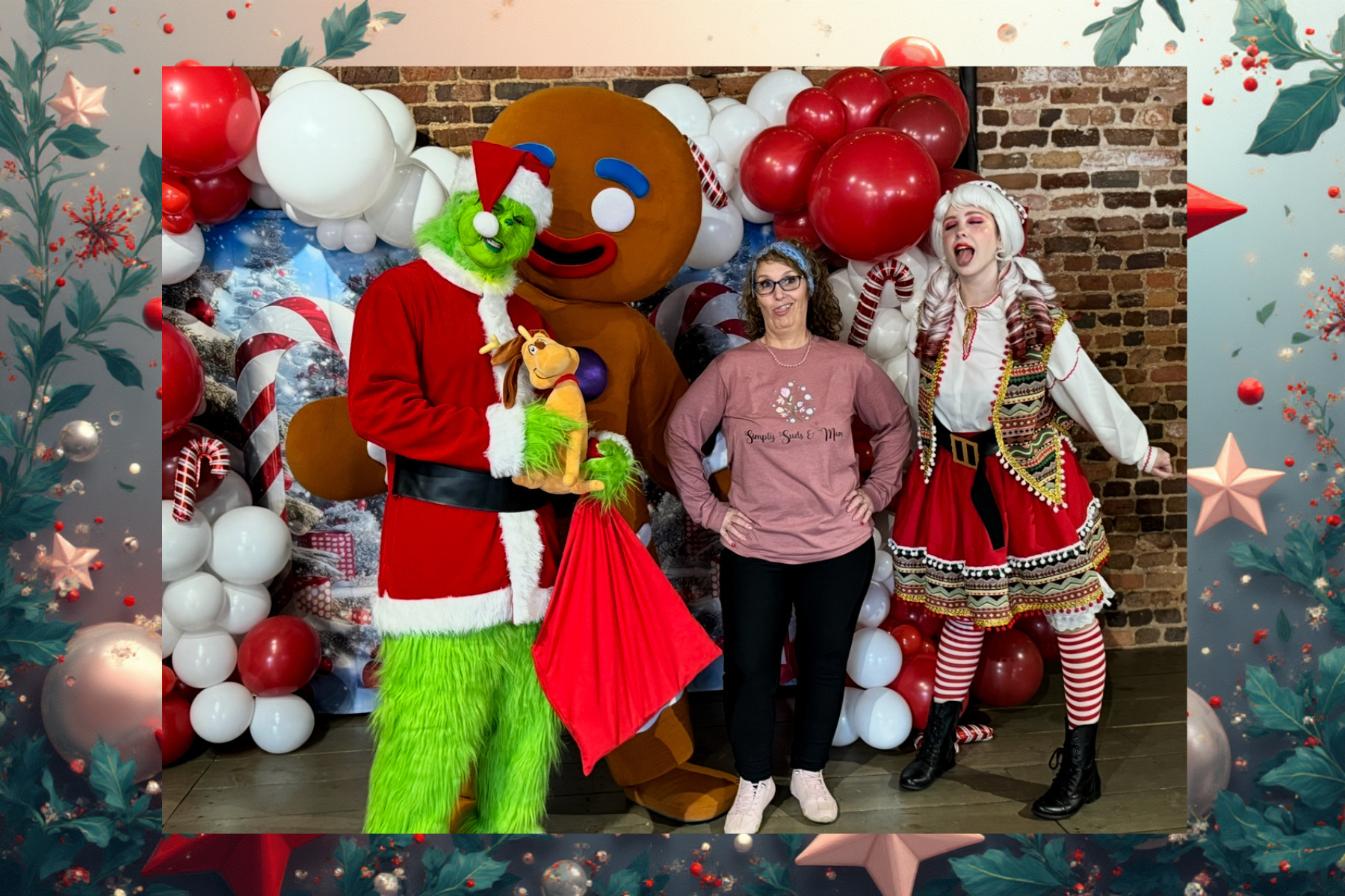 Four people posing at a festive backdrop with balloons, including two colorful costumed characters