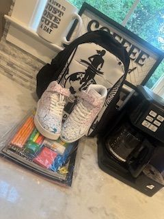 Nike sneakers on a kitchen counter beside a coffee mug and black cordless phone