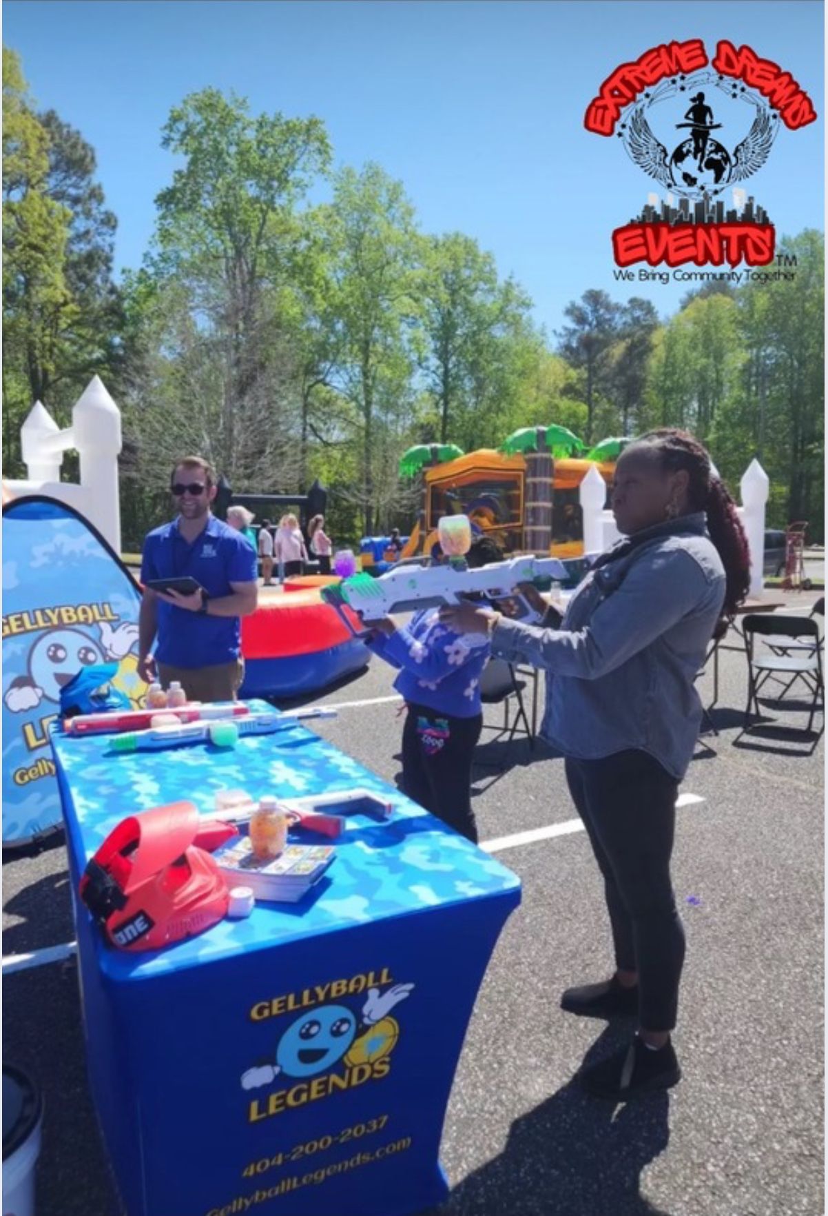 Outdoor carnival game booth with a woman tossing a ball at colorful prizes on a sunny day