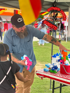 Vendor handing out colorful toys at an outdoor event booth