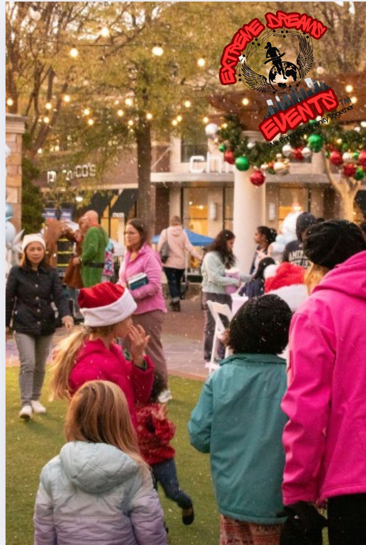 Children and adults dancing outdoors at a festive holiday event with lights and decorations