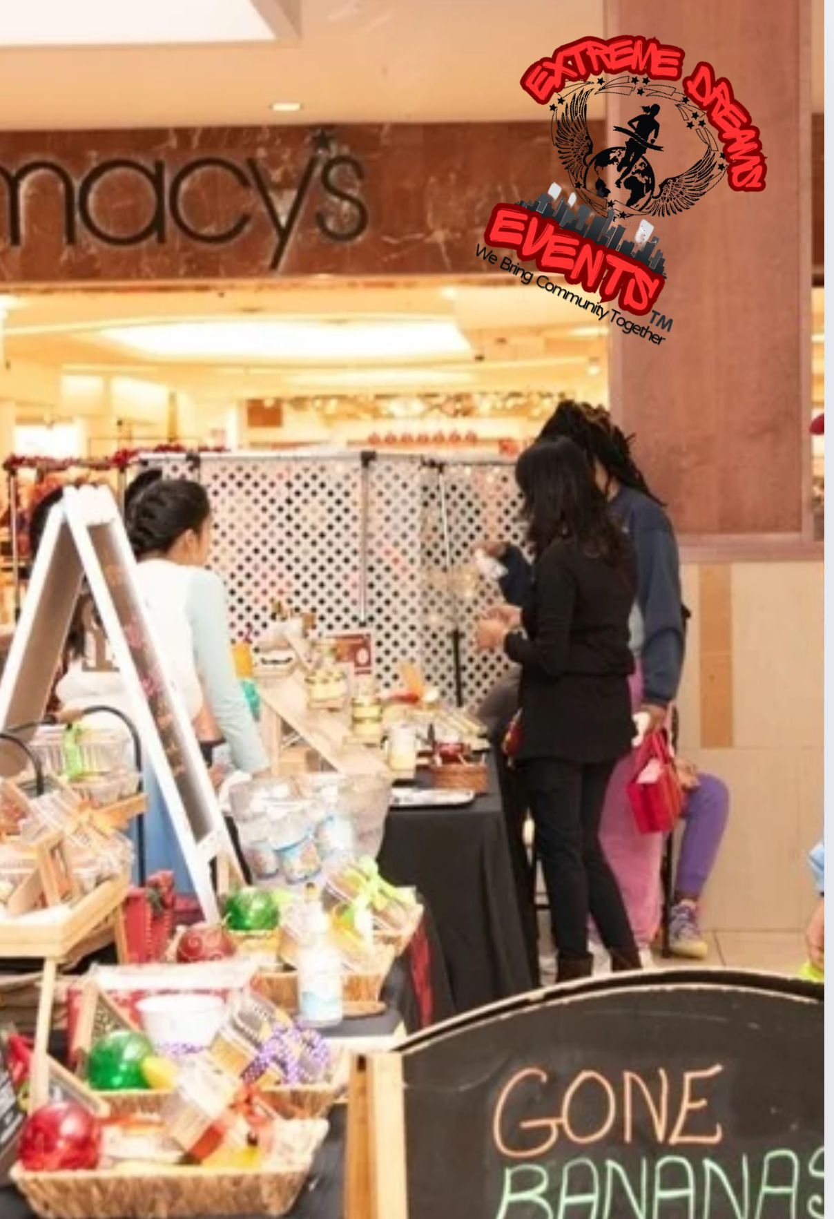 Macy’s entrance with a small produce stand and a chalkboard sign reading “GONE BANANAS”
