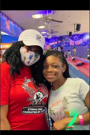 Two people smiling together at a bowling alley with neon lights and lanes in the background
