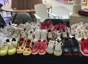 Assorted colorful sneakers displayed in rows on a table at an indoor market or shop.