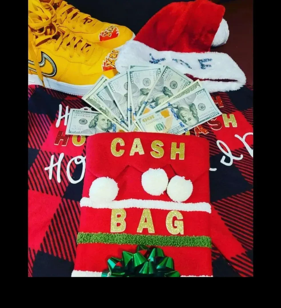 Red holiday cash bag with dollar bills, red Santa hat, and yellow sneakers on a red-and-black plaid background