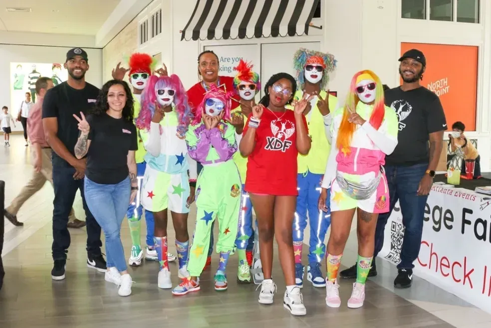 Group of costumed clowns posing and walking indoors at an event venue
