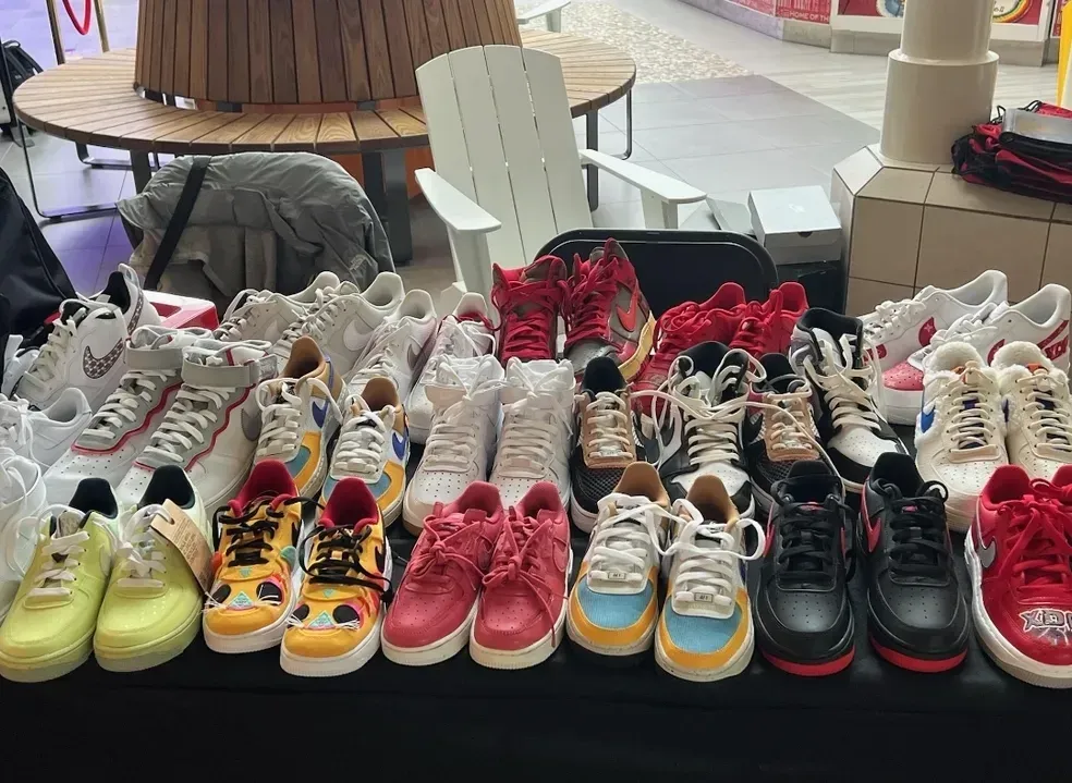Rows of colorful sneakers displayed on a table in a store or market setting.