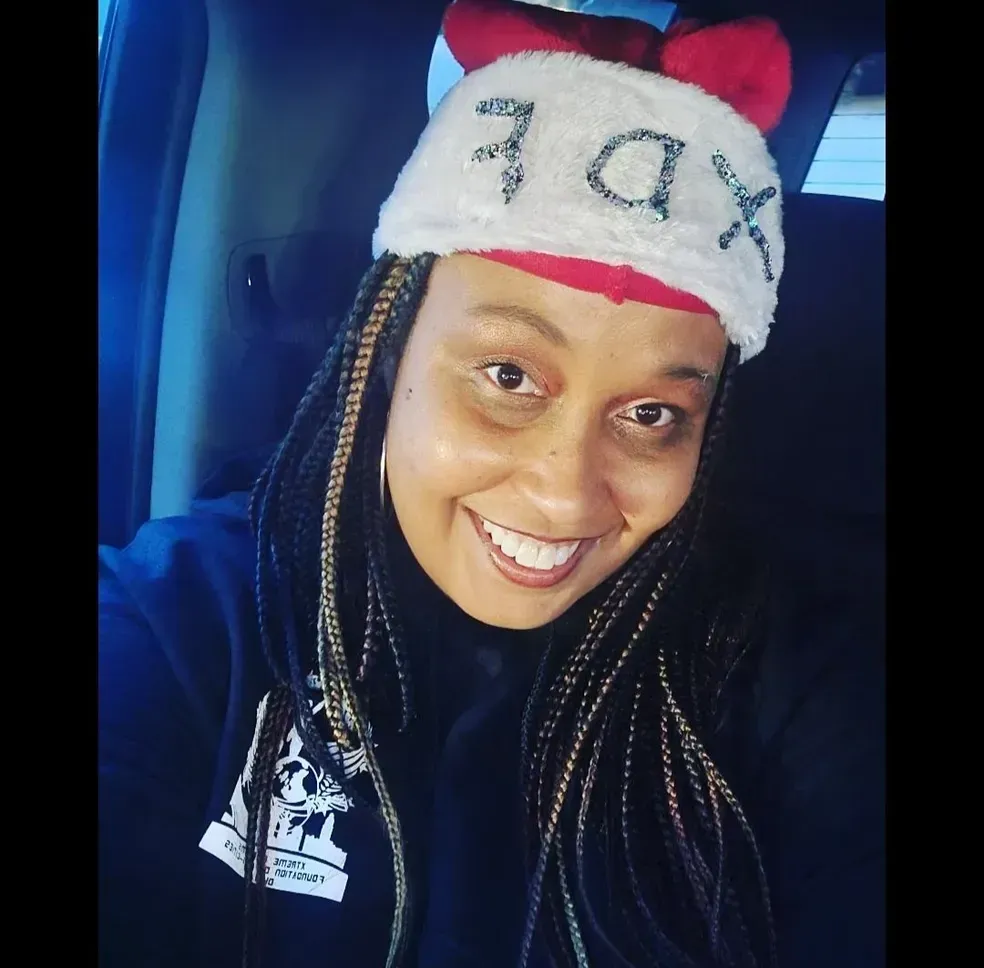 Smiling person wearing a red-and-white Santa hat and black hoodie in a car