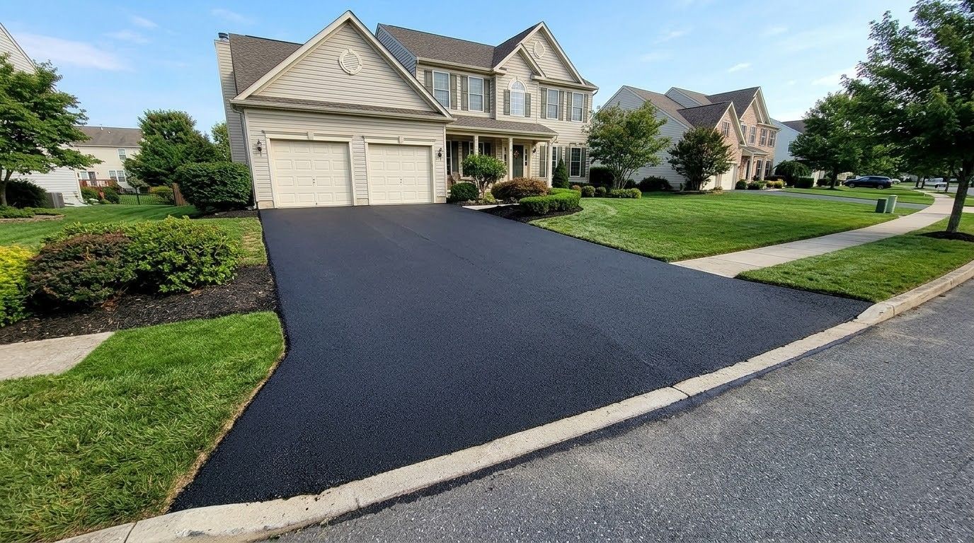 Suburban house with a freshly paved black driveway, white garage, and landscaped front yard