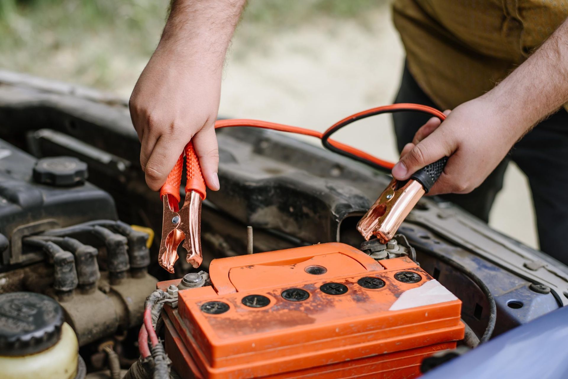 Person connecting jumper cables to a car battery.